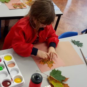 student laying leaf onto paper